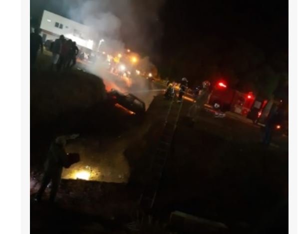 Carro cai em valeta e pega fogo. Vítimas são retiradas com a ajuda de populares