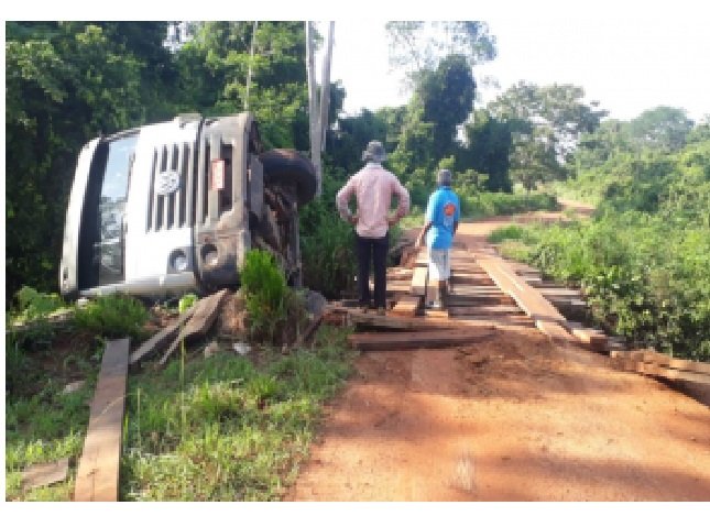 Caminhão basculante carregado com pedras tomba em ponte na zona rural