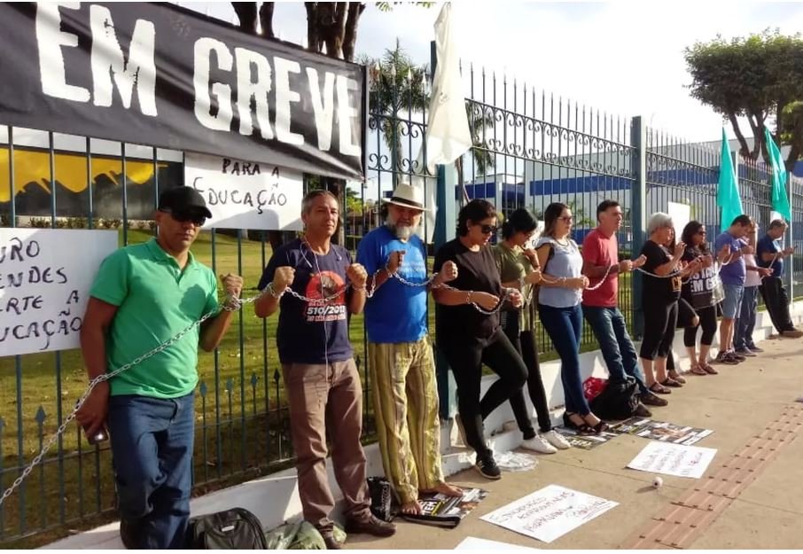 Servidores da Educação em greve se acorrentam em protesto na frente da sede do governo em Cuiabá